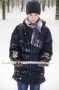 Teenager boy in a blue jacket, in a checkered scarf and in a dark blue hat with a icicle in his hands Royalty Free Stock Photo