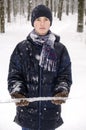 Teenager boy in a blue jacket, in a checkered scarf and in a dark blue hat with a icicle in his hands Royalty Free Stock Photo