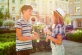 Teenager boy congratulates the girl with bouquet of flowers outdoors.