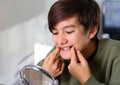 Teenager boy with diastema overbite teeth missing gap problem wearing orthodontic appliance treatment infront of the mirror.