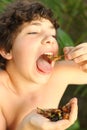 Teenager boy with disgust grimace hold unusial strange thai food roasted insects