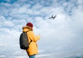 Teenager boy dressed yellow jacket piloting a modern digital drone using remote controller