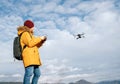 Teenager boy dressed yellow jacket piloting a modern digital drone using remote controller