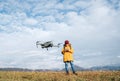 Teenager boy dressed yellow jacket piloting a modern digital drone using remote controller