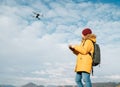 Teenager boy dressed yellow jacket piloting a modern digital drone using remote controller