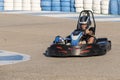 a teenager boy driving a kart at the exit of a curve of a karting circuit, face of speed and concentration while driving a go-kart