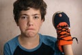 Teenager boy frustrated about hole in his favourite trainers shoes