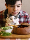 Teenager boy with funny cute cat eating dinner - russian beatroot soup borsch with sourcream and dill close up photo isoaltee on w Royalty Free Stock Photo