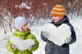 Teenager boy and girl keep hearts from snow