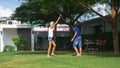 A teenager boy and girl play badminton on a green lawn in the backyard of their home Royalty Free Stock Photo