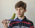 Teenager boy with a green budgerigar