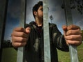 Teenager boy hands holding strong iron bars. Immigrant and refugee crisis. Seen from above. Dramatic border fence or prison concep