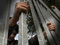 Teenager boy hands holding strong iron bars. Seen from below. Immigrant and refugee crisis. Dramatic border fence or prison concep Royalty Free Stock Photo