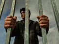 Teenager boy hands holding strong iron bars. Seen from below. Immigrant and refugee crisis. Dramatic border fence or prison concep