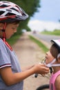 Teenager boy helping preschooler girl to put on safety helmet. Active outdoor sport for child. Royalty Free Stock Photo
