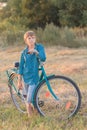 Teenager boy holding bike in farm field