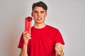 Teenager boy holding birthday gift over isolated background annoyed and frustrated shouting with anger, crazy and yelling with Royalty Free Stock Photo