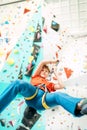 Teenager boy at indoor climbing wall hall. Boy is climbing using an auto belay system and climbing harness. Active teenager time