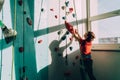 Teenager boy at indoor climbing wall hall starting climbing. Boy using climbing harness and chalk powder when somebody belaying