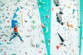 Teenager boy at indoor climbing wall hall. Boy is climbing using an auto belay system and climbing harness. Active teenager time