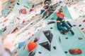 Teenager boy at indoor climbing wall hall. Boy is climbing using a top rope and climbing harness and somebody belaying him from