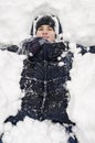 Teenager boy lies in deep snow under a heavy snowfall