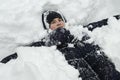 Teenager boy lies in deep snow under a heavy snowfall