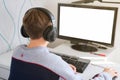 Teenager boy wearing earphones looking at computer monitor. computer screen mockup.