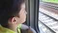 A teenager boy looking through the window and watching landscapes while riding in moving train