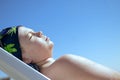 Teenager boy lying in the sun closing his eyes sunbathes on a sea beach. Caucasians attractive child on a blue sky background,