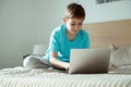 Teenager boy playing, studying or having online meeting using laptop in bed room during homeschooling while coronavirus quarantine