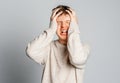 Teenager boy pressing firmly hands to temples experiencing bad headache, having shut eyes because of pain, standing gray Royalty Free Stock Photo