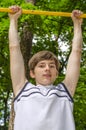 Teenager boy pulls up on a horizontal bar