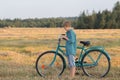 Teenager boy pushing bicycle in farm field Royalty Free Stock Photo