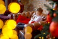 Teenager boy with rabbit in hands on background of new year tree. Child celebrates Christmas. Happy smiling child with pet in arms