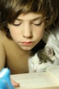 Teenager boy reading book with cat in bed Royalty Free Stock Photo