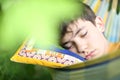Teenager boy resting sleep with book in hammock on summer green garden Royalty Free Stock Photo