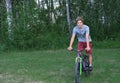 Teenager boy riding a bike in a park. curly teenager on a bicycle Royalty Free Stock Photo