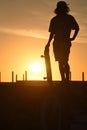 Teenager boy silhouette with skate board at sunset Royalty Free Stock Photo