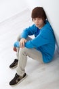 Teenager boy sitting on the floor by the wall Royalty Free Stock Photo