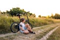 Teenager boy sitting near bicycle on a country road at sunset Royalty Free Stock Photo