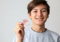 Teenager boy smiling holding orthodontic appliance dental treatment to improving bite gap.