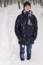 Teenager boy stands in deep snow under a heavy snowfall