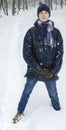 Teenager boy stands in deep snow under a heavy snowfall