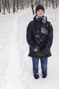 Teenager boy stands in deep snow under a heavy snowfall