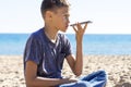 Teenager boy using a smart phone voice recognition function online, using cell phone to send a voice message on the Royalty Free Stock Photo