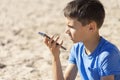 Teenager boy using a smart phone voice recognition function online, using cell phone to send a voice message sitting on Royalty Free Stock Photo