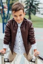 Teenager boy is waiting for the stairs at the railing. Fashionable kid in stylish city clothes.