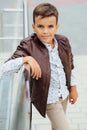 Teenager boy is waiting for the stairs at the railing. Fashionable kid in stylish city clothes.