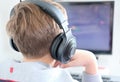 Teenager boy wearing earphones looking at computer monitor. Royalty Free Stock Photo